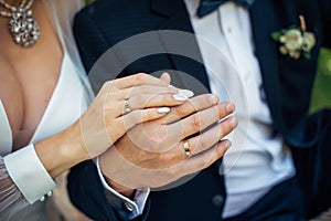 Hands of the bride and groom close-up, blurred background. Gold wedding rings on the fingers of newlyweds. Concept of marriage