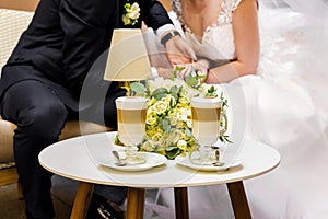 Hands of the bride and groom for a cup of coffee. Wedding bouquet on the table.