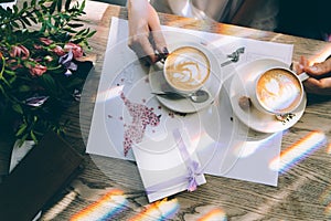 Hands of the bride and groom for a cup of coffee. Wedding bouquet on the table.