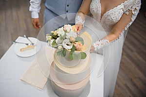 Hands of bride and groom cut of a slice of a wedding cake