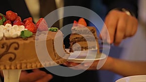 Hands of bride and groom cut of a slice of a wedding cake. Cut the wedding cake. people cut and put the cake on a plate