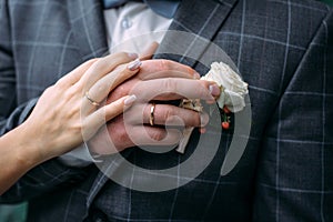 Hands of the bride and groom with elegant manicure, close-up. Wedding rings of the newlyweds, couple on wedding day, touching