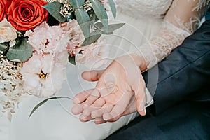 Hands of the bride and groom with rings on the background of a wedding bouquet