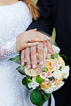 Hands of the bride and groom with rings on a beautiful wedding bouquet