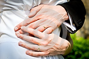 Hands of bride and groom with rings during the summer wedding.