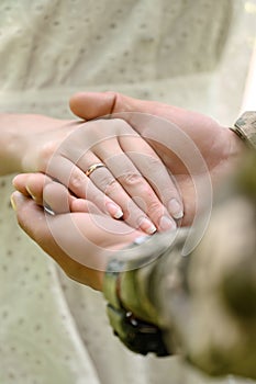 Hands of the bride and groom with rings on their fingers close-up. Groom in military uniform.