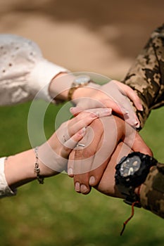 Hands of the bride and groom with rings on their fingers close-up. Groom in military uniform.