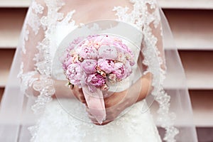 Hands of a bride holding peonies bouquet