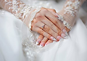 Hands of a bride with a ring and a wedding manicure