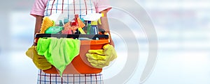 Hands with bucket of cleaning products.