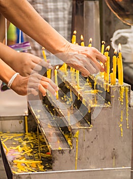 Hands of Buddhists lighting up the candles on altar to pay their