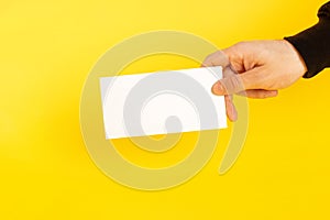 Hands with business card. Hand holding a white card on a coloured yellow background
