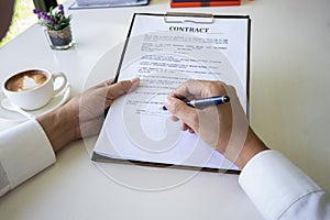 Hands of business man signing the contract document with pen on desk