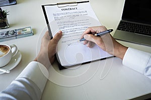 Hands of business man signing the contract document with pen on desk