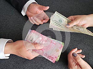 hands of business man and woman exchanging chilean banknotes and american dollars bills