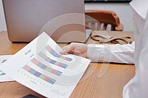 Hands of business woman analyzing charts or paperwork on workplace in office.