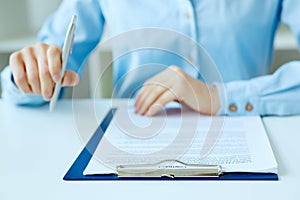 Hands of business woman signing the contract document with pen on desk close-up. Selective focus image on sign a