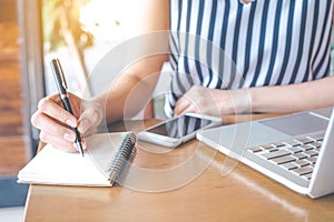 The hands of a business woman working at a computer and writing