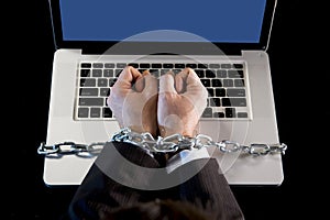 Hands of businessman addicted to work bond with chain to computer laptop in workaholic