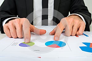 Hands of a businessman analysing two pie graphs