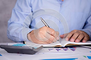 Hands of businessman calculate tax with calculator while laptop computer on desk.