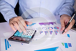 Hands of businessman calculate tax with calculator while laptop computer on desk.