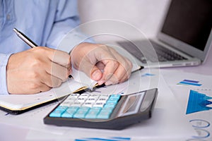 Hands of businessman calculate tax with calculator while laptop computer on desk.