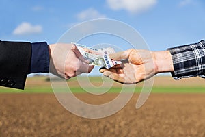 Hands of a businessman and farmer with a money transfer