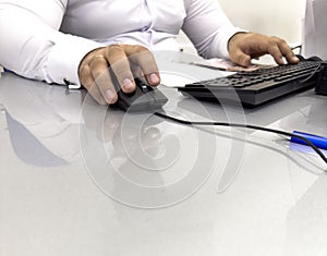 Hands of businessman holding computer mouse and keyboard in office. Male office worker focused on a computer work. Hand on