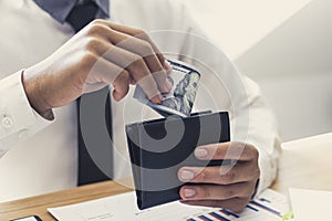 Hands of a businessman holding a dollar banknote in a black purse received from the financial and accounting success his company e