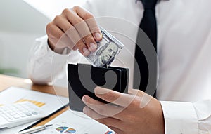 Hands of a businessman holding a dollar banknote in a black purse received from the financial and accounting success his company e