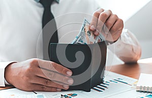 Hands of a businessman holding a dollar banknote in a black purse received from the financial and accounting success his company e