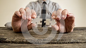 Hands of a businessman holding puzzle pieces
