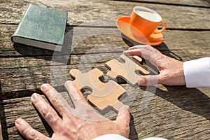 Hands of a businessman holding two jigsaw puzzle pieces