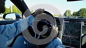 Hands of businessman holds steering wheel while driving electric car at city. Male businessperson operating electrical