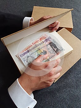 hands of a businessman with Honduran money and books on the table