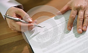 Hands of businessman with pen signing contract document at table closeup