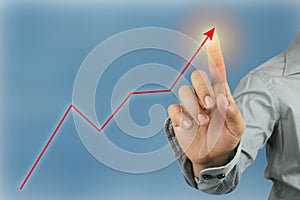 Hands of businessman point to the top of bar graph and skyscraper background.