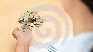 Hands of businessman putting coin into plant sprouting growing up to profit, demonstrating financial growth through saving plans