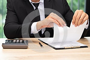 Hands of businessman ripping loan agreement at the desk, break t