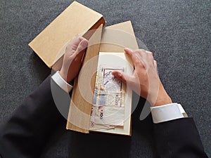 hands of a businessman with uruguayan money and books on the table