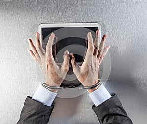 Hands of businessman using a digital tablet with slave handcuffs