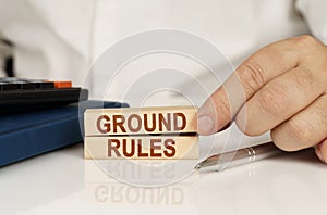 In the hands of a businessman, wooden blocks with the inscription - GROUND RULES
