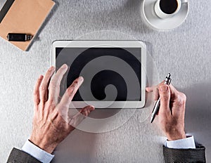 Hands of businessman working with tablet on desk, top view