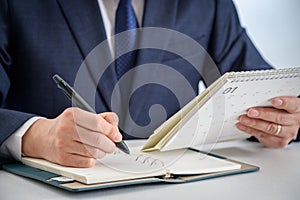 Hands of a businessman writing a schedule or recording ideas in a diary