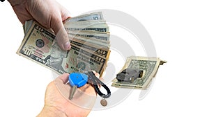 The hands of the car dealer make an exchange between the car keys and the customer`s money. With