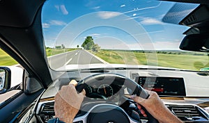 Hands of car driver on steering wheel, road trip, driving on highway road