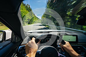 Hands of car driver on steering wheel, road trip, driving on highway road