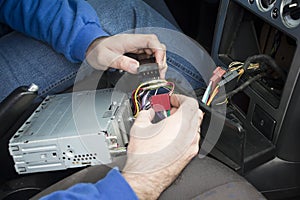 The hands of the car electrician connect radio to the car`s electrical system.