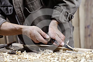 Hands of carpenter with a hammer and chisel on workbench in carpentry